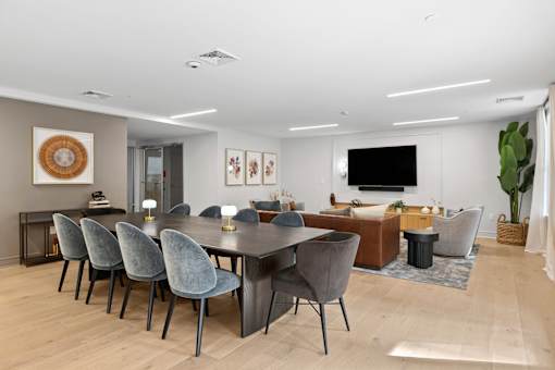 A modern dining room with a large table and grey chairs.