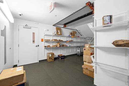 A storage room with white shelves and boxes on the floor.