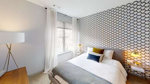A bedroom with a large bed and a patterned wallpaper.