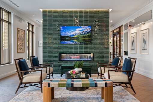 A living room with a green tiled wall and a large screen TV.
