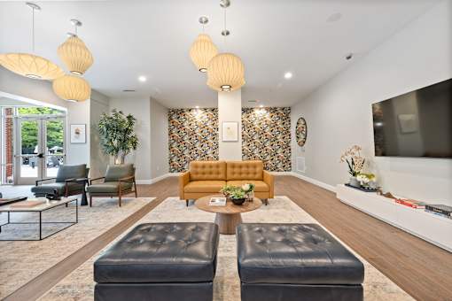 A living room with a leather ottoman and a yellow sofa.