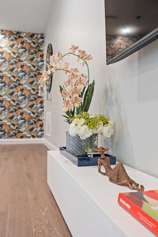 A vase with flowers sits on a shelf next to a book.