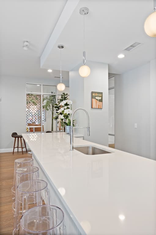A kitchen with a white counter top and a bar stool.