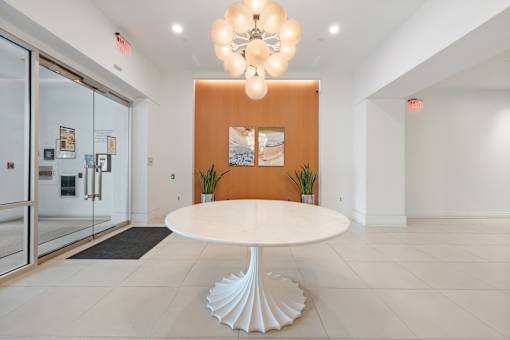 A white table with a wooden top is in the middle of a room with a chandelier hanging from the ceiling.