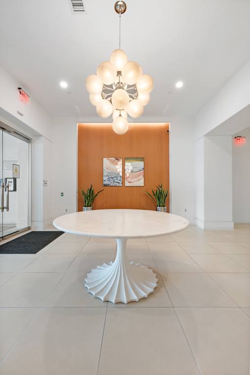 A white table with a chandelier hangs in a room with orange walls.