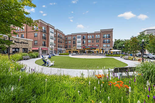 A grassy area with flowers in the foreground and a building in the background.