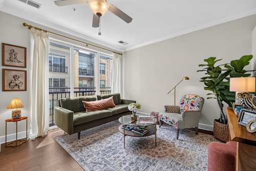 A living room with a green couch, a coffee table, and a ceiling fan.