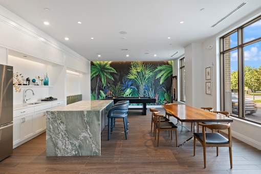 A kitchen with a marble island and a dining table with chairs.