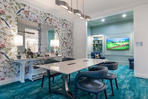 A room with a floral wallpapered wall and a white table with chairs.