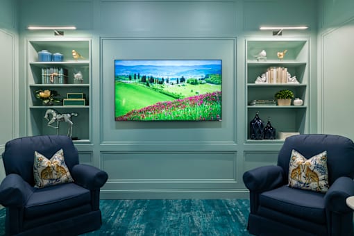 Two blue chairs are placed in front of a television in a room.