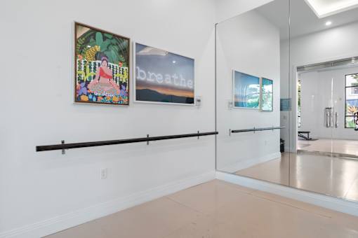 A white room with a mirror and two paintings on the wall.
