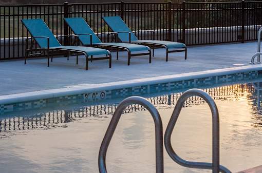A pool with a metal ladder and four lounge chairs.