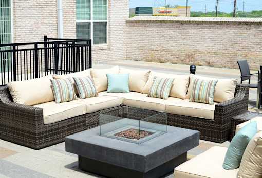 A patio with a couch, pillows, and a fire pit.