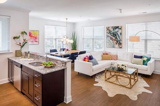A modern kitchen with a white countertop and a white couch with colorful pillows.