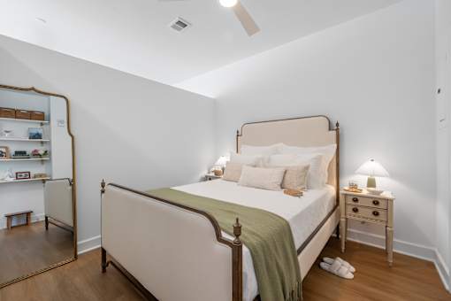 A bedroom with a bed, nightstand, and a mirror.