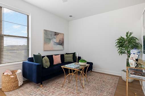 A living room with a blue couch and a painting on the wall.