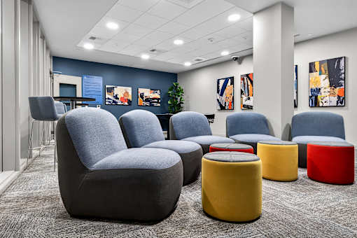 A modern waiting area with grey and yellow chairs and ottomans.