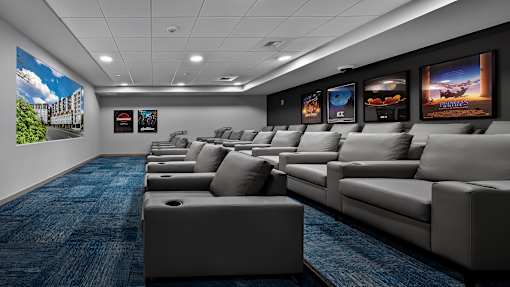 A row of grey sofas are lined up in a room with a blue carpet.