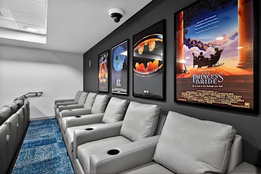 A row of white couches are lined up in a room with posters on the wall.
