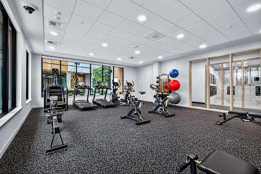 A gym with a variety of equipment including treadmills, exercise bikes, and weights.
