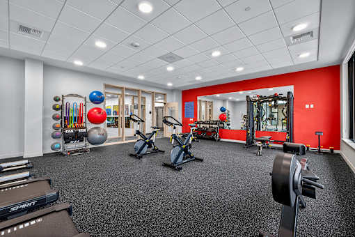 A gym with a variety of equipment including weights, a treadmill, and a stationary bike.
