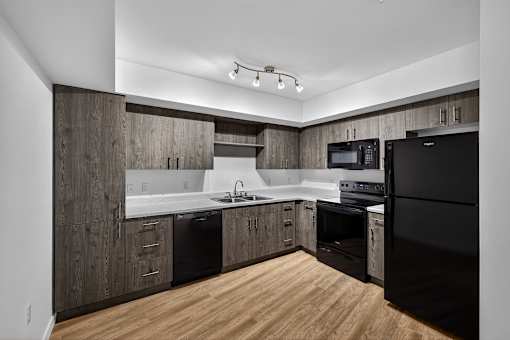 A modern kitchen with dark wood cabinets and black appliances.