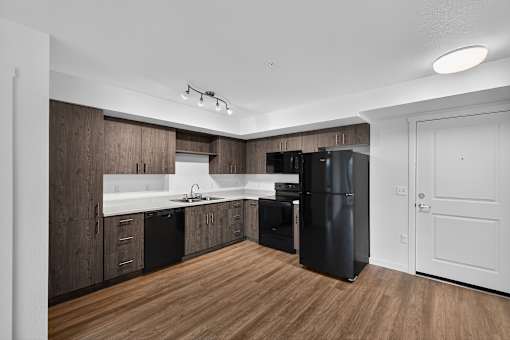 A modern kitchen with dark wood cabinets and a black refrigerator.