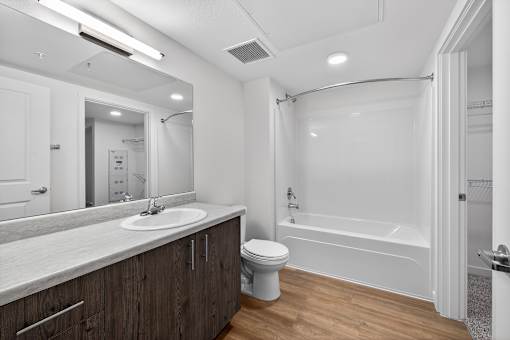 A modern bathroom with a white tub and wooden cabinets.