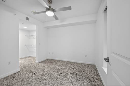 A room with a ceiling fan and carpeted floor.