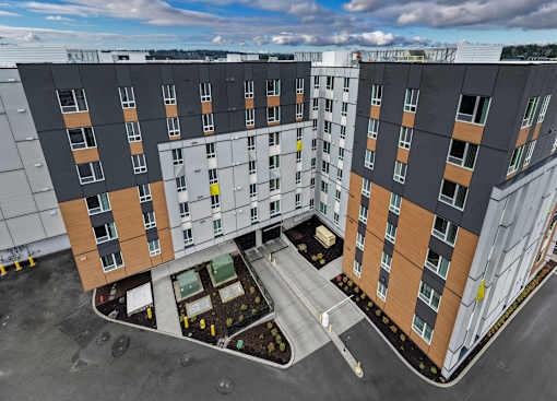 A modern apartment complex with a parking lot in front.