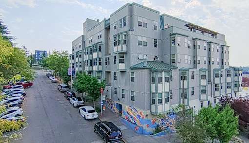 A street view of a residential area with apartment buildings and parked cars.