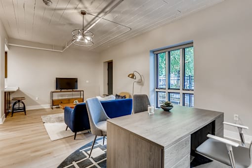 A room with a desk and chairs in front of a window.