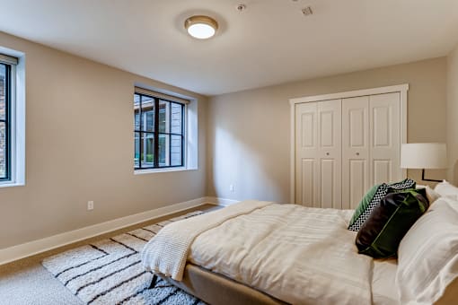 A bedroom with a bed, pillows, and a striped rug.