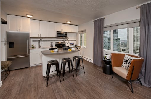 A modern kitchen with a refrigerator, stove, and bar stools.