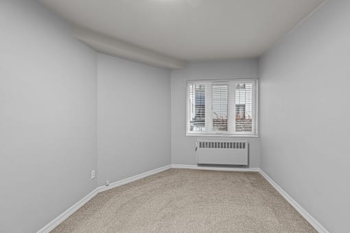 A room with a window and a radiator on the floor.