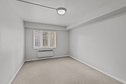 A room with a window and a carpeted floor.