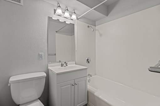 A white bathroom with a toilet, sink, and bathtub.