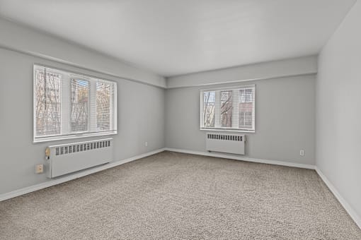 A room with a carpeted floor and two windows.