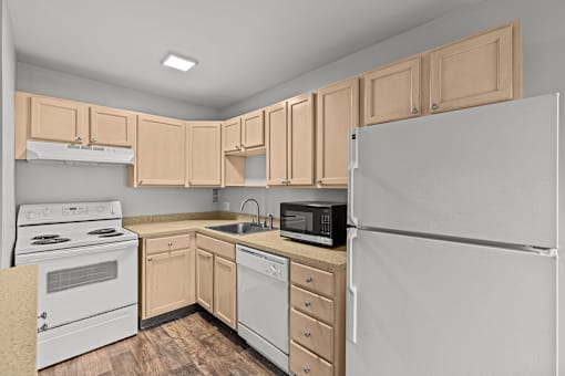 A kitchen with a white refrigerator, white oven, and wooden cabinets.