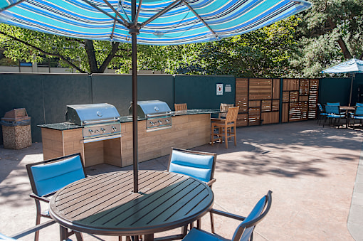 A table and chairs set up under a blue umbrella.