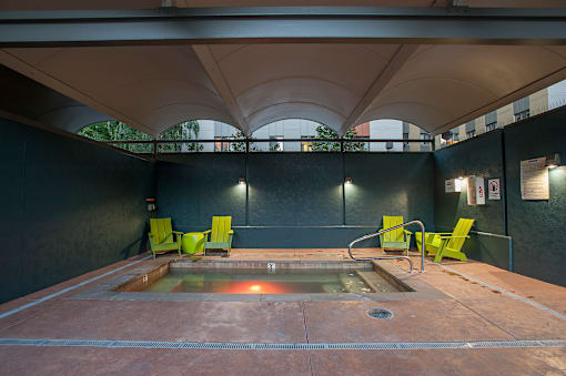 A hot tub is surrounded by four chairs in a room with a black wall.