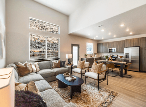 A modern living room with a grey sofa, a coffee table, and a kitchen in the background.