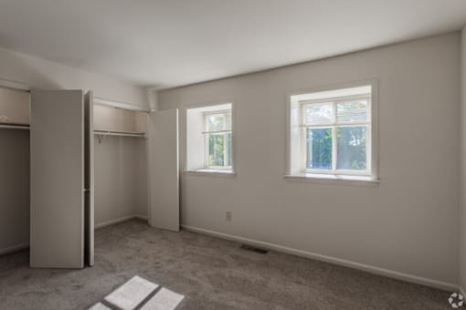 a bedroom with two windows and a closet