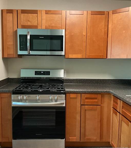 A kitchen with a stove and microwave above it.
