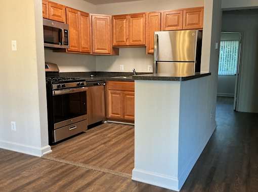 A kitchen with wooden cabinets and a stainless steel refrigerator.