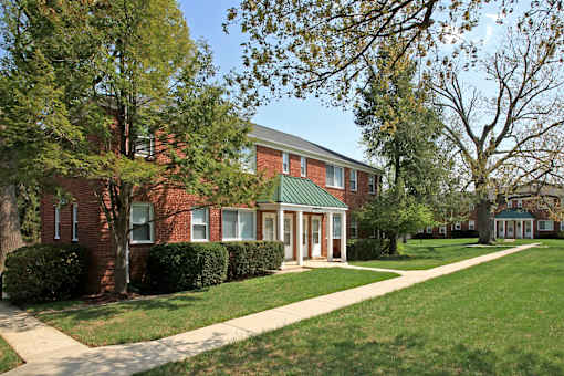 A red brick building with a green roof and a walkway in front.