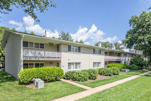 A white apartment building with green bushes in front.