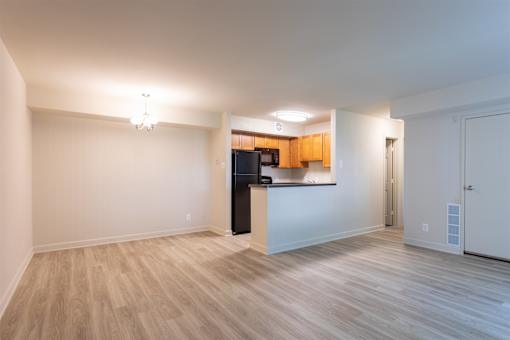 A spacious room with wooden flooring and a kitchenette in the corner.