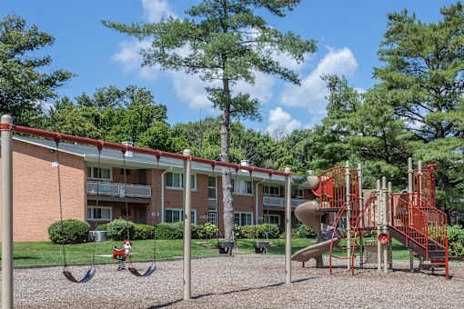 A playground with a red swing set and a red slide.