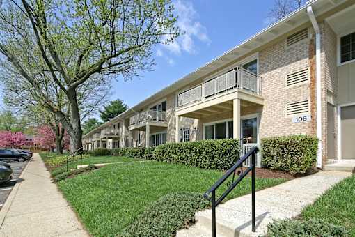 Apartment building number 100 with a tree in front.